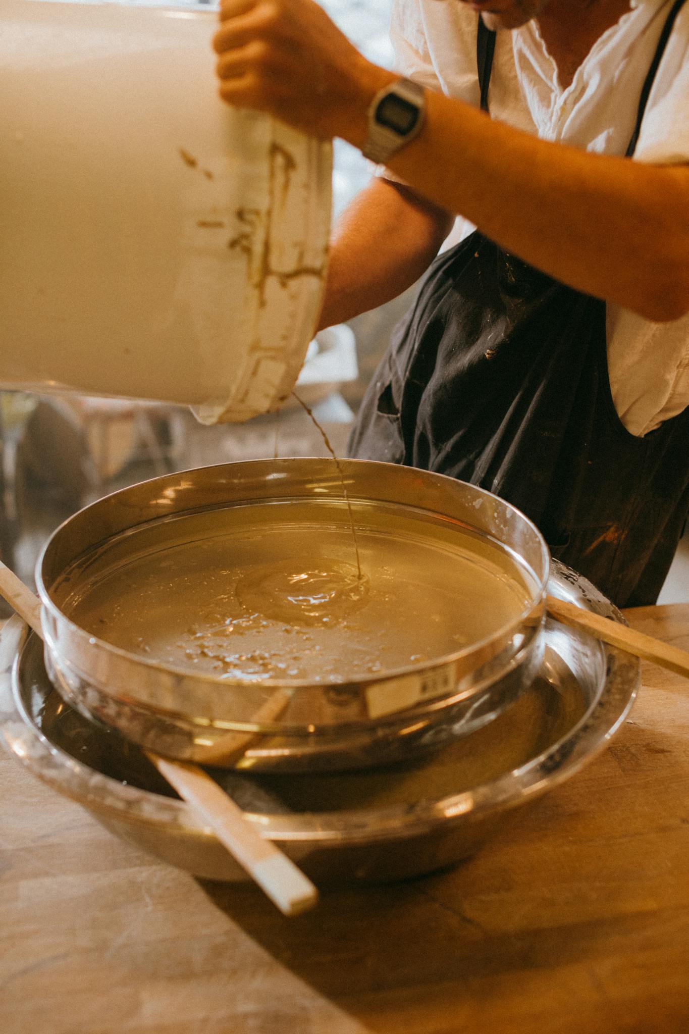 Artisan pouring liquid into mold, showcasing craftsmanship in ceramics workshop.